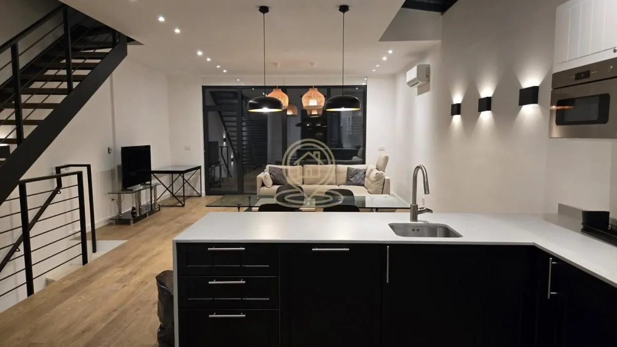 View from the kitchen towards the open-plan living room and dining area with stairs.