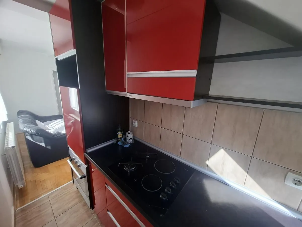 Kuhinja sa crvenim elementima i ugradnom pločom.