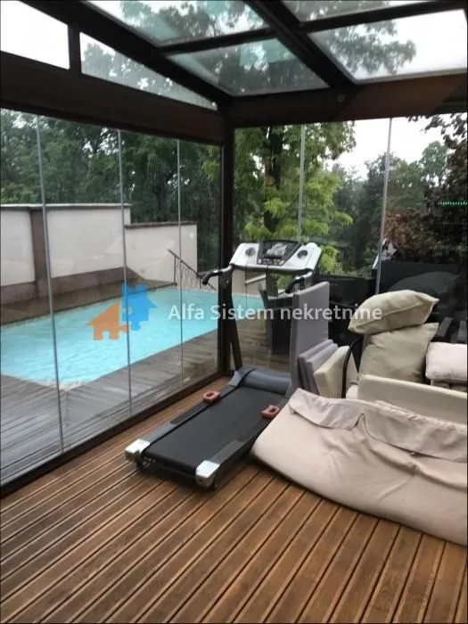 Glazed terrace with wooden flooring, a treadmill, and a view of the swimming pool.