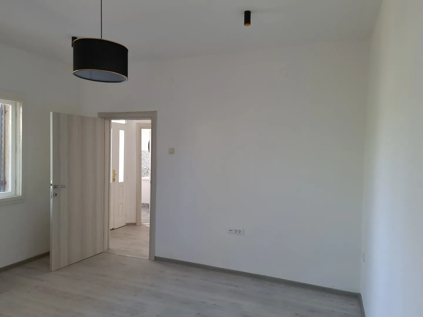 Empty bright room with white walls and wooden flooring.