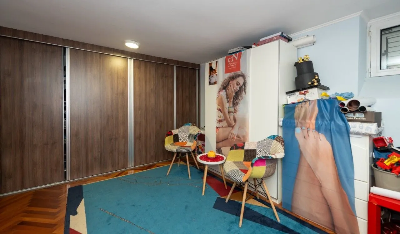 Bedroom with a large built-in wardrobe, colorful armchairs, and a rug.