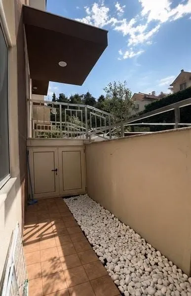 Dvorište sa popločanim dijelom i bijelim šljunkom pored objekta.