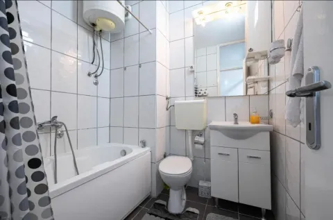 Small bathroom with a bathtub, sink, and toilet. - image 16