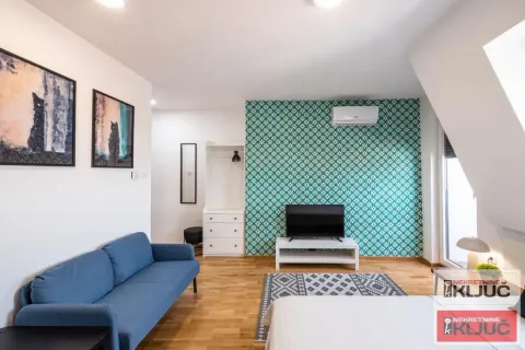 Prostrana spavaća soba sa krevetom, plavom sofom i TV-om na zidu sa ukrasnim tapetama. - image 4