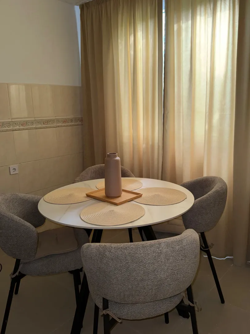 Dining area with a round table and four grey chairs.