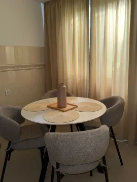 Dining area with a round table and four grey chairs. - image 4