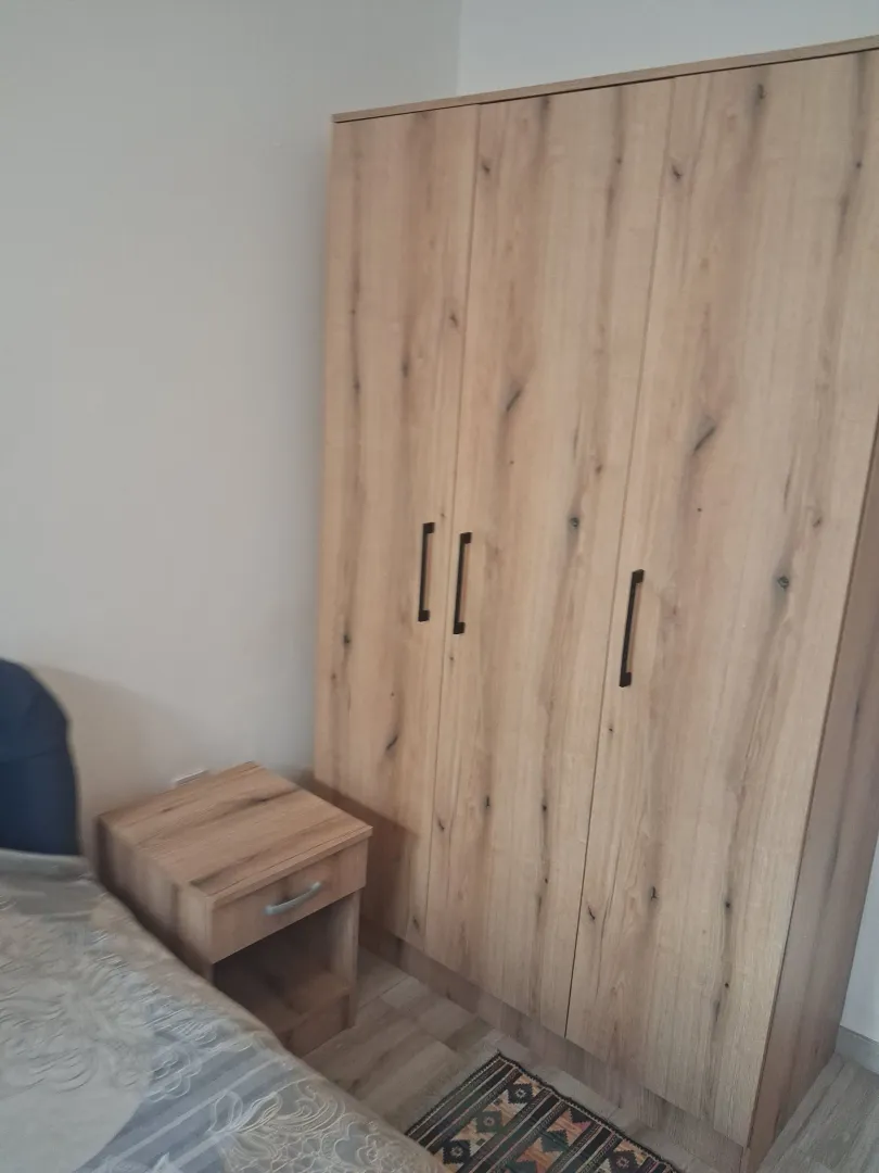 Bedroom with a large wooden wardrobe and a nightstand.
