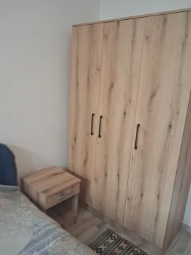 Bedroom with a large wooden wardrobe and a nightstand. - image 6