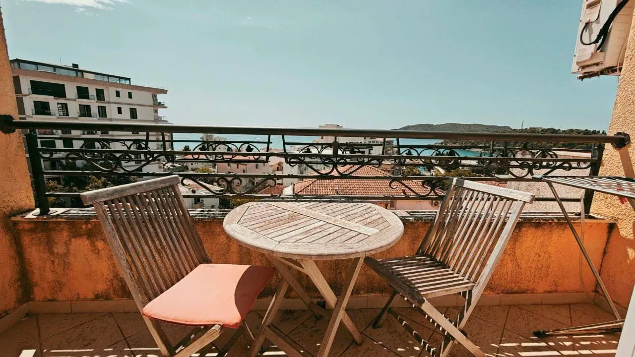 Furnished terrace with a table, chairs, and a view of the city and sea.