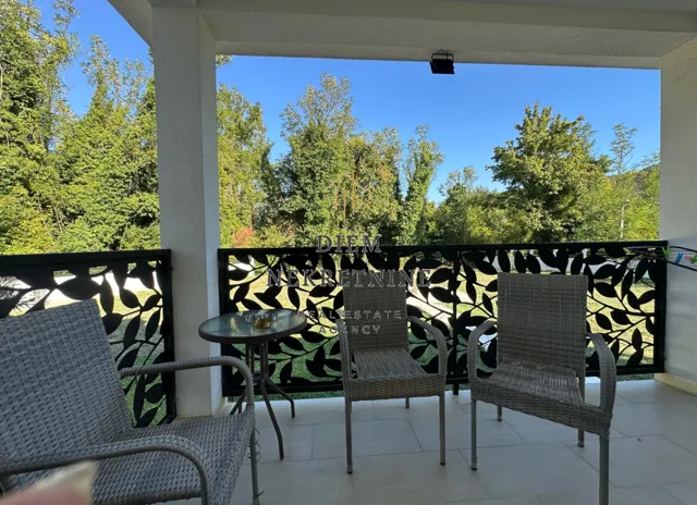 Covered terrace with seating furniture and green views.
