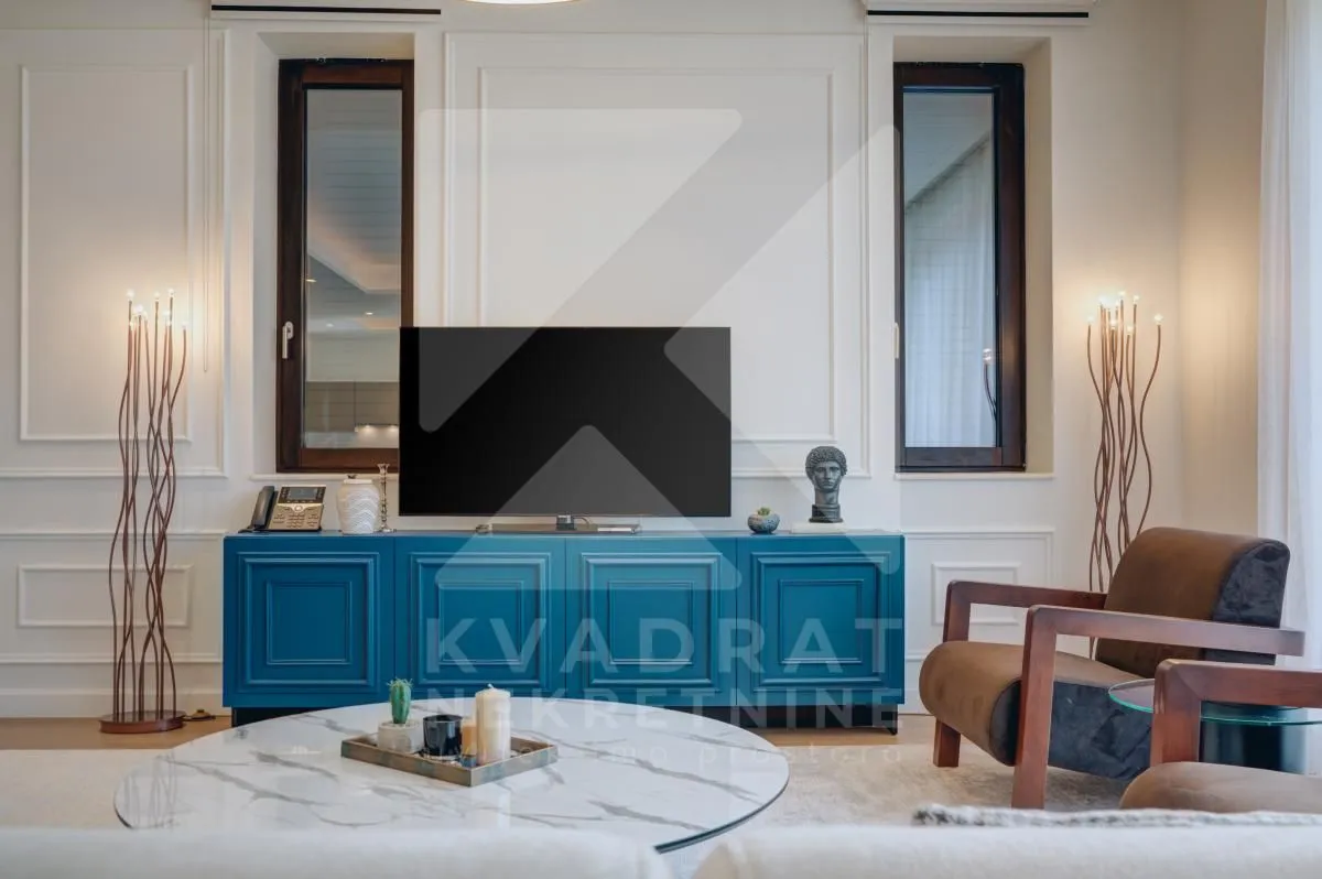 Dnevna soba sa plavom komodom, televizorom i foteljama.