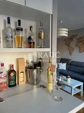 View of part of the living room with a bar counter and bottles of drinks. - image 4