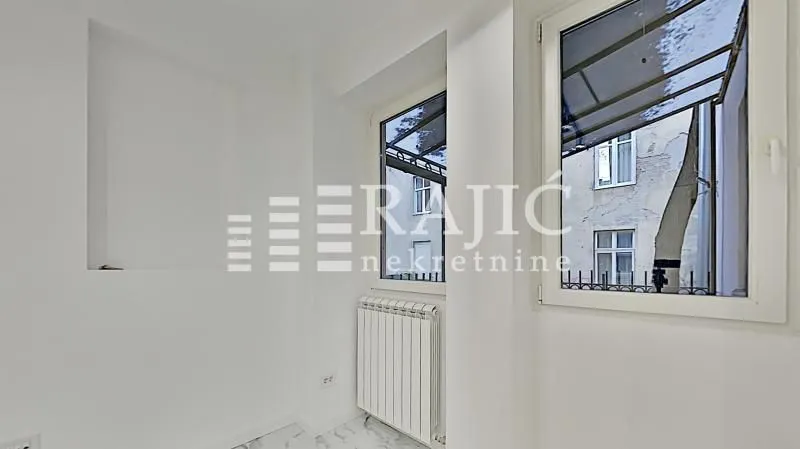 Empty bright room with windows and a radiator.