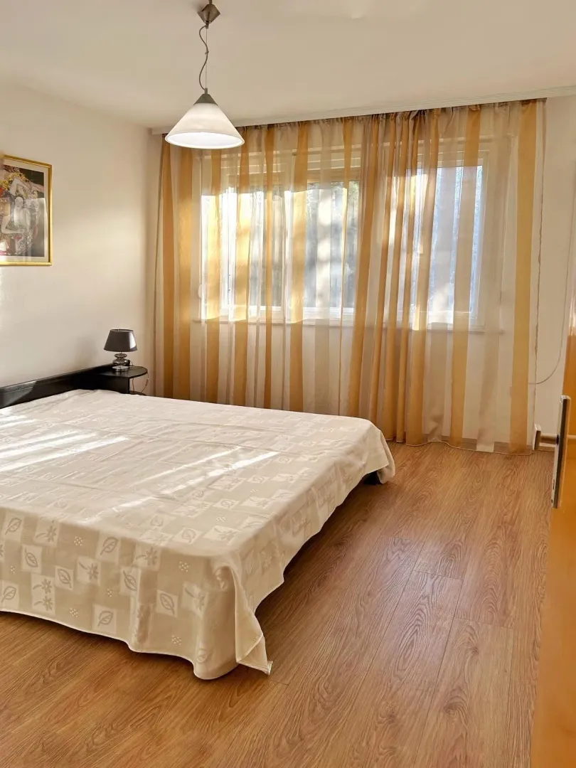 Svijetla spavaća soba sa bračnim krevetom i laminatom.
