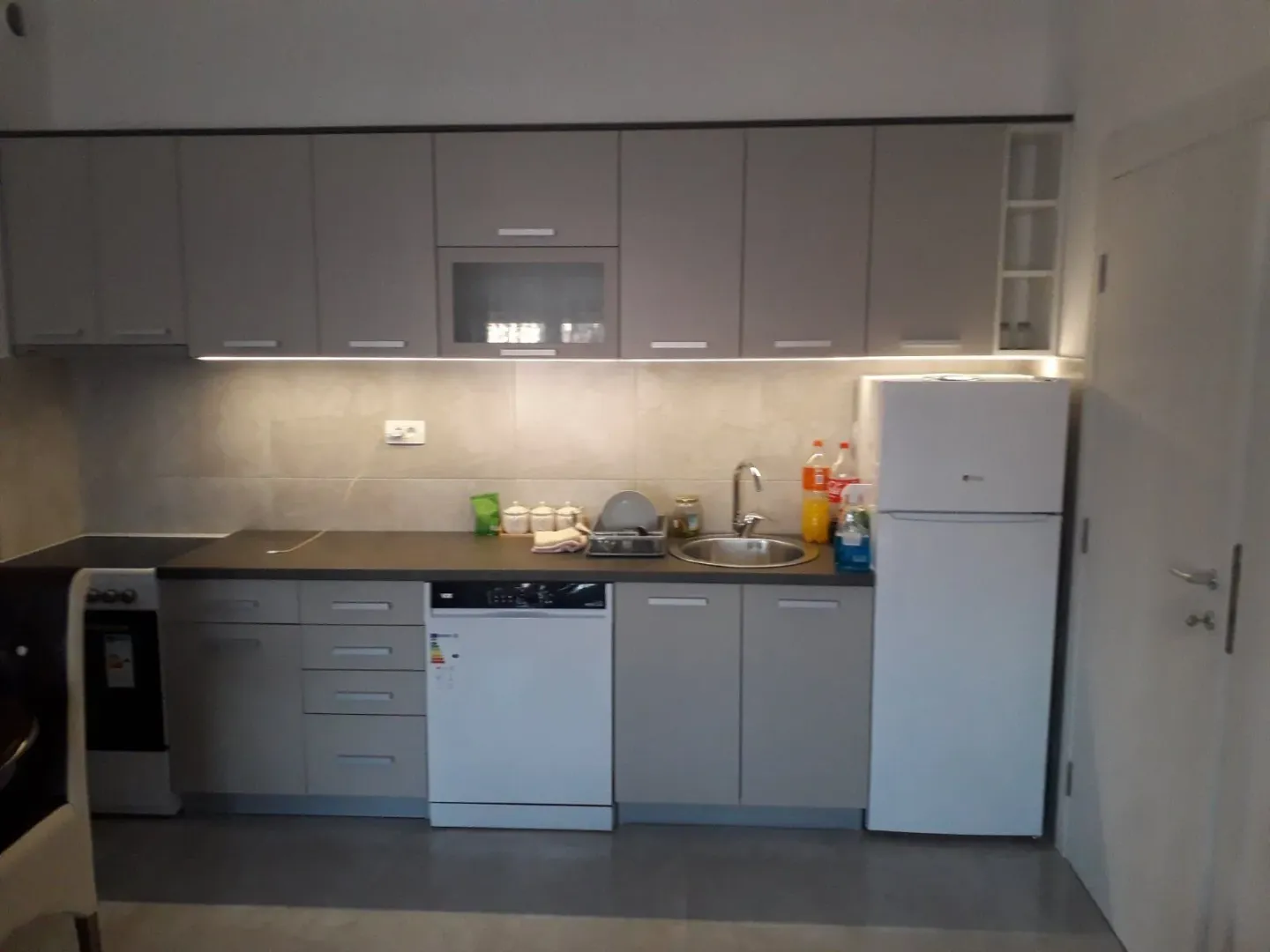 Moderna kuhinja sa sivim elementima i bijelom tehnikom.