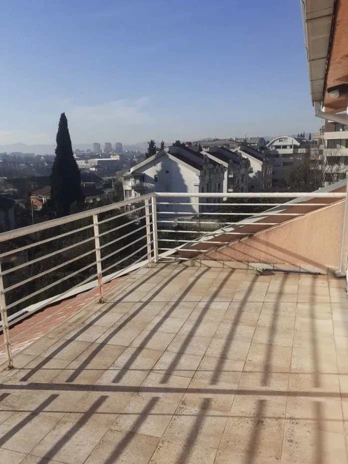 Prostrana terasa sa popločanim podom i pogledom na grad.