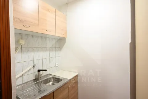 Small kitchen with a sink and wooden cabinets. - image 6