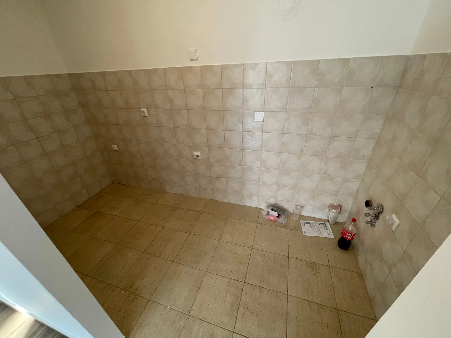 Prazna prostorija obložena pločicama sa instalacijama za vodu.
