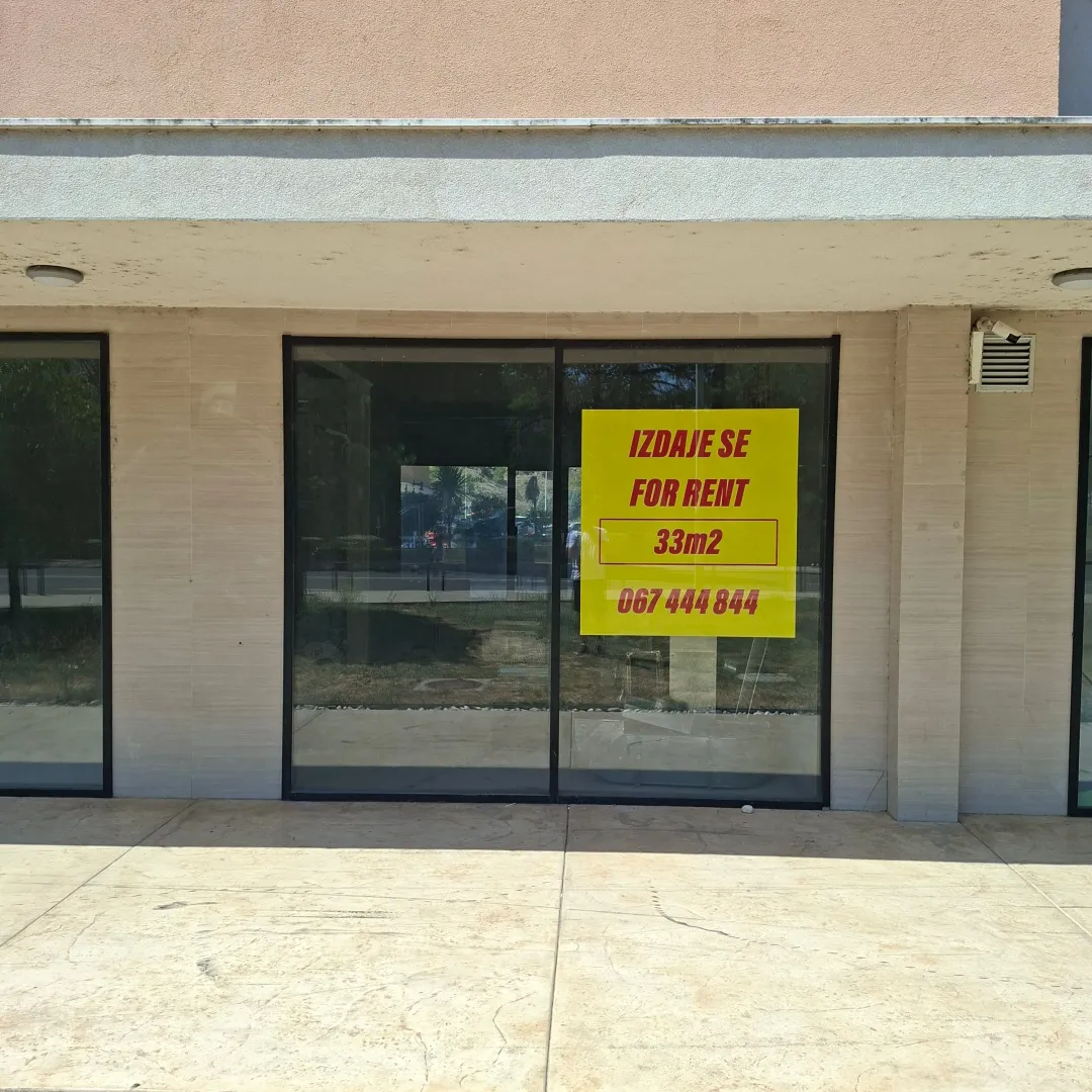 Facade of a commercial space with a large glass shopfront and a for rent sign.