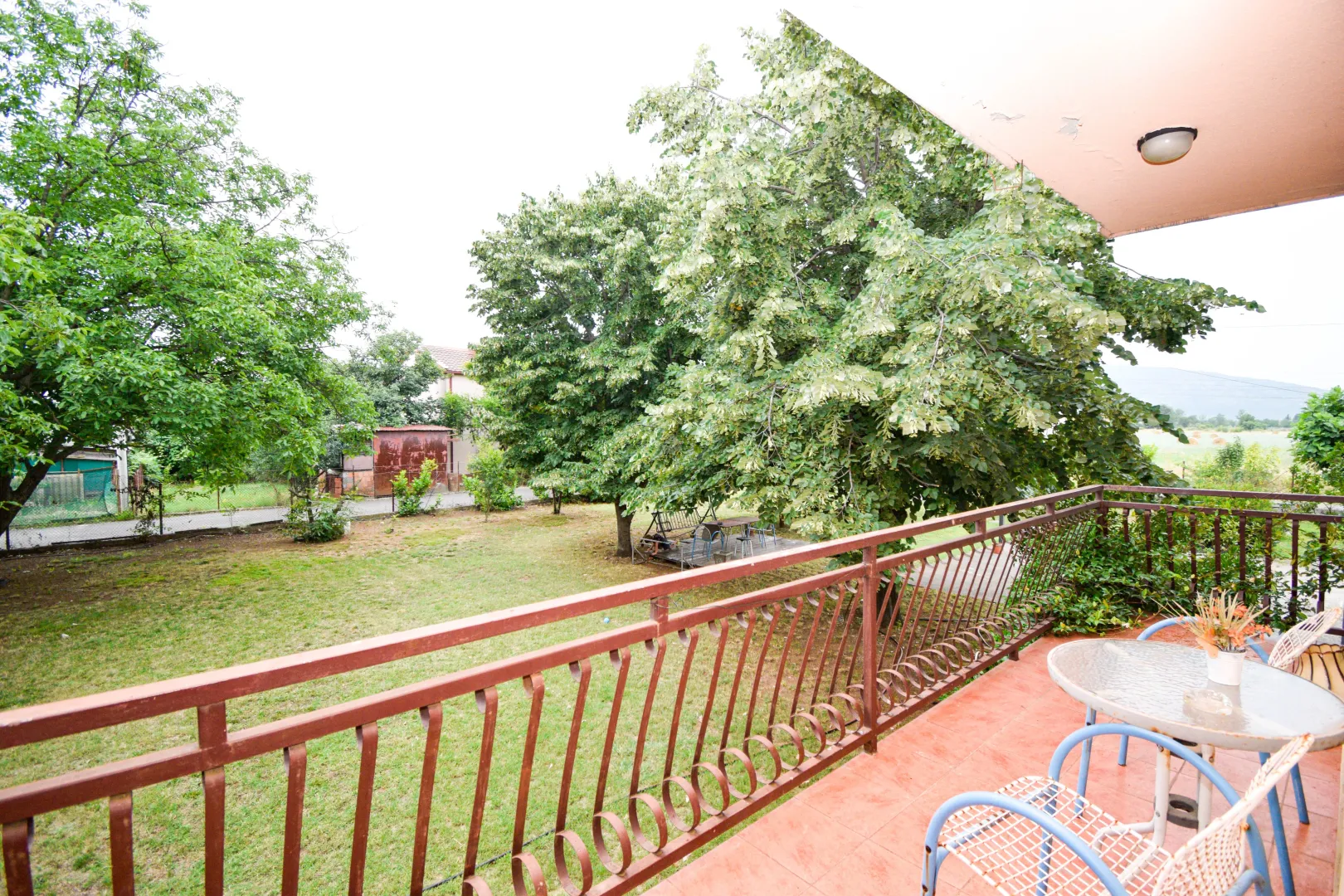 Balcony with seating furniture and a view of the green yard.