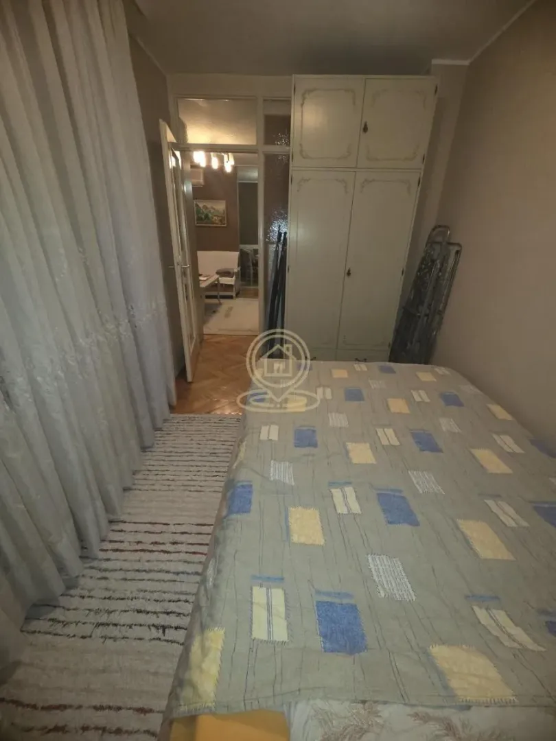 Manja spavaća soba sa krevetom i ugradnim ormarom.