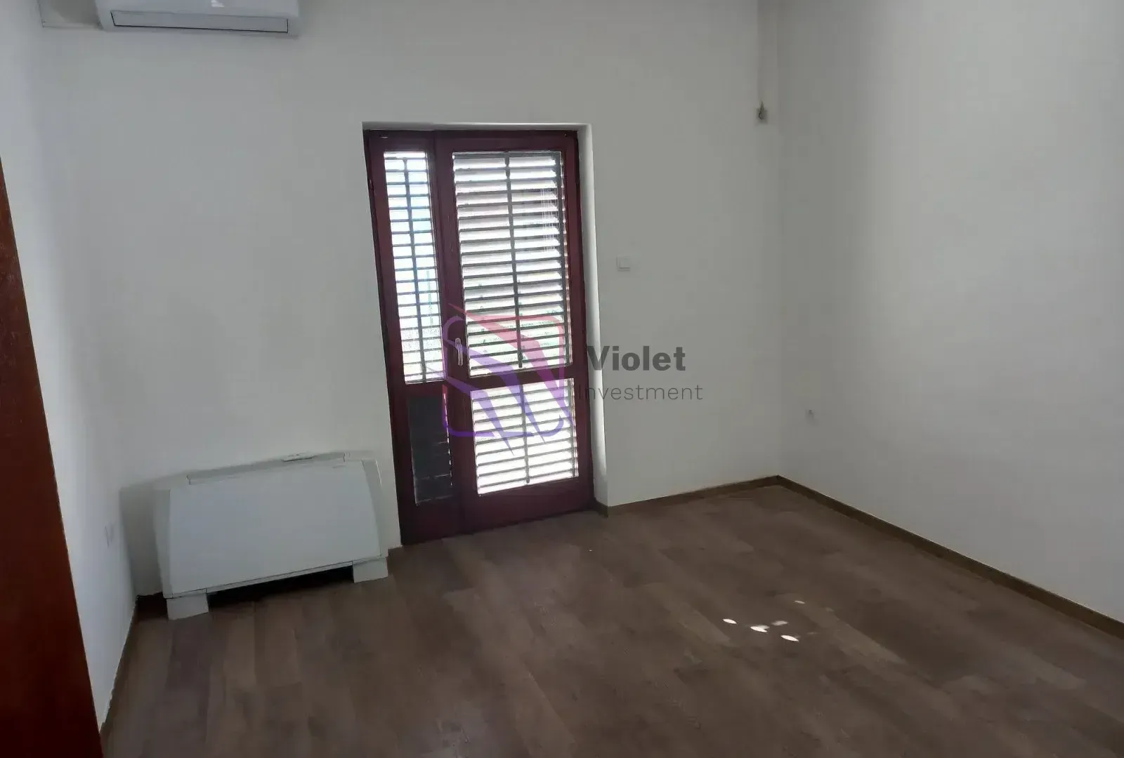 Empty room with wooden flooring, air conditioning unit, and a door leading to the terrace.