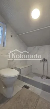 Kupatilo obloženo keramičkim pločicama sa tuš kabinom i klozetskom šoljom. - image 2