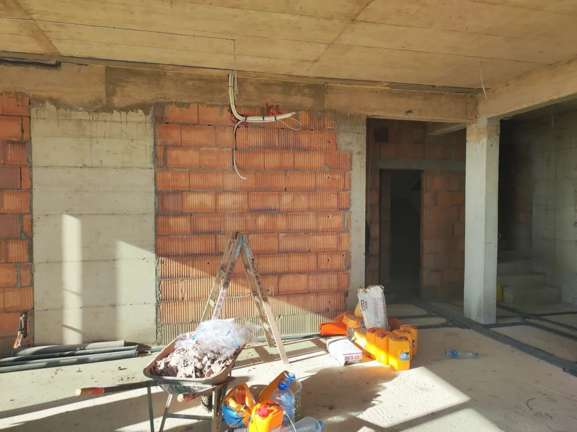 Pogled na prostoriju u fazi izgradnje sa građevinskim materijalom i alatima.