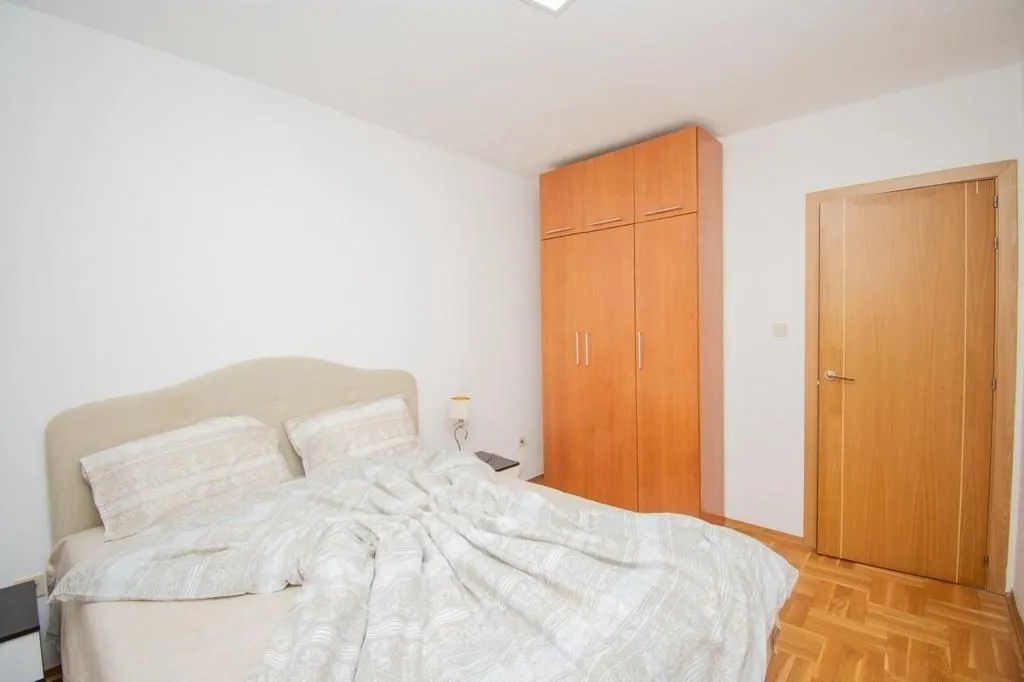 Bright bedroom with a double bed and a wooden wardrobe.