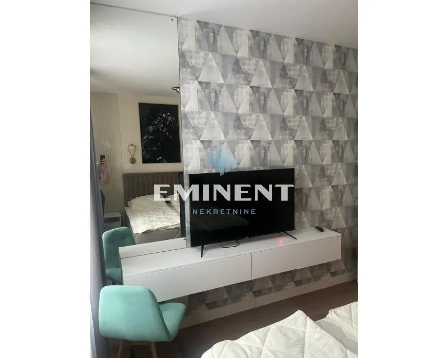 Bedroom with a double bed, TV, and decorative wallpaper.