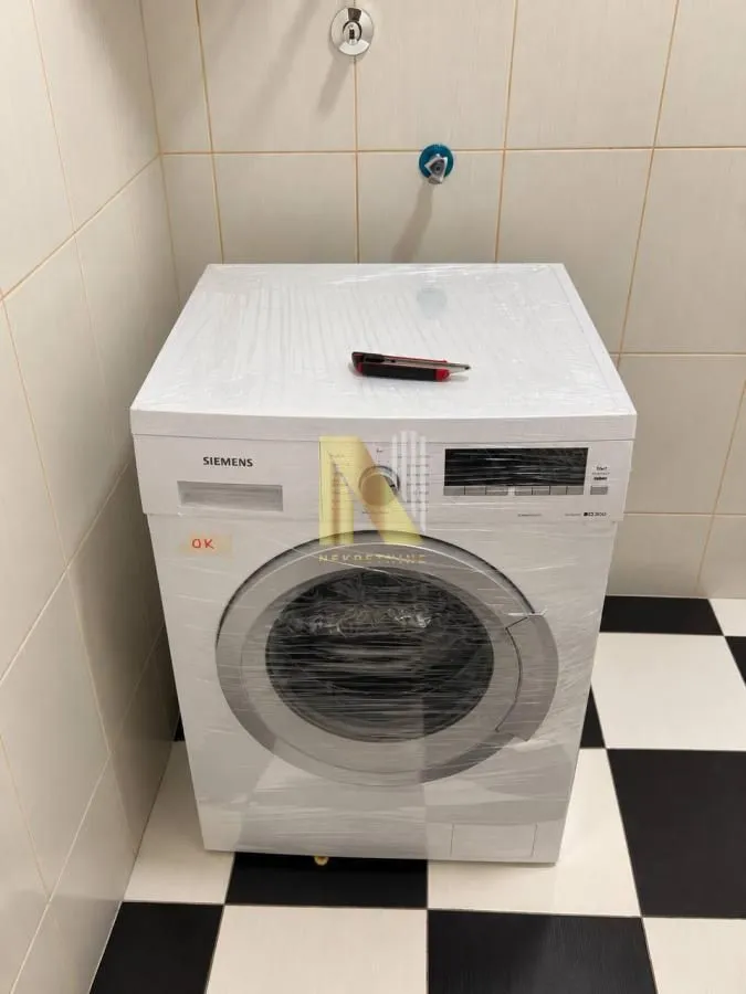 Nova veš mašina u kupatilu sa pločicama.