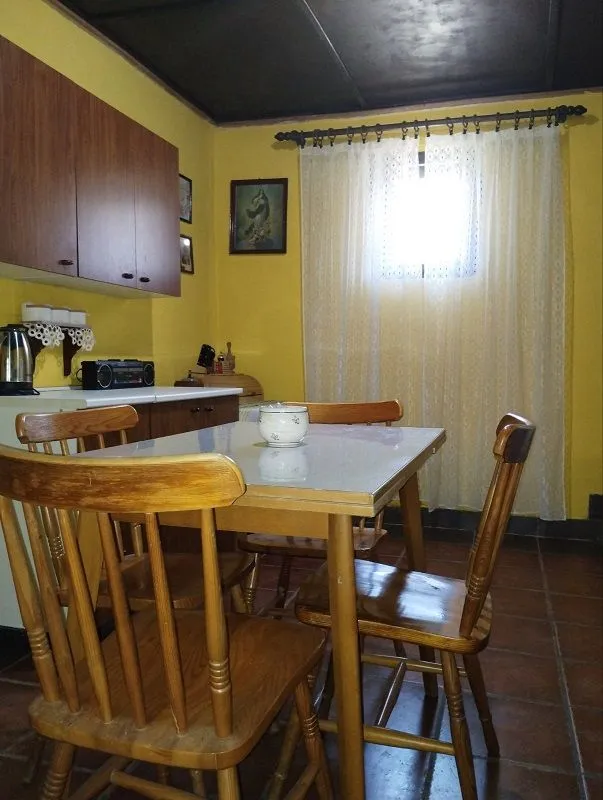 Trpezarijski sto sa stolicama u kuhinji sa žutim zidovima.