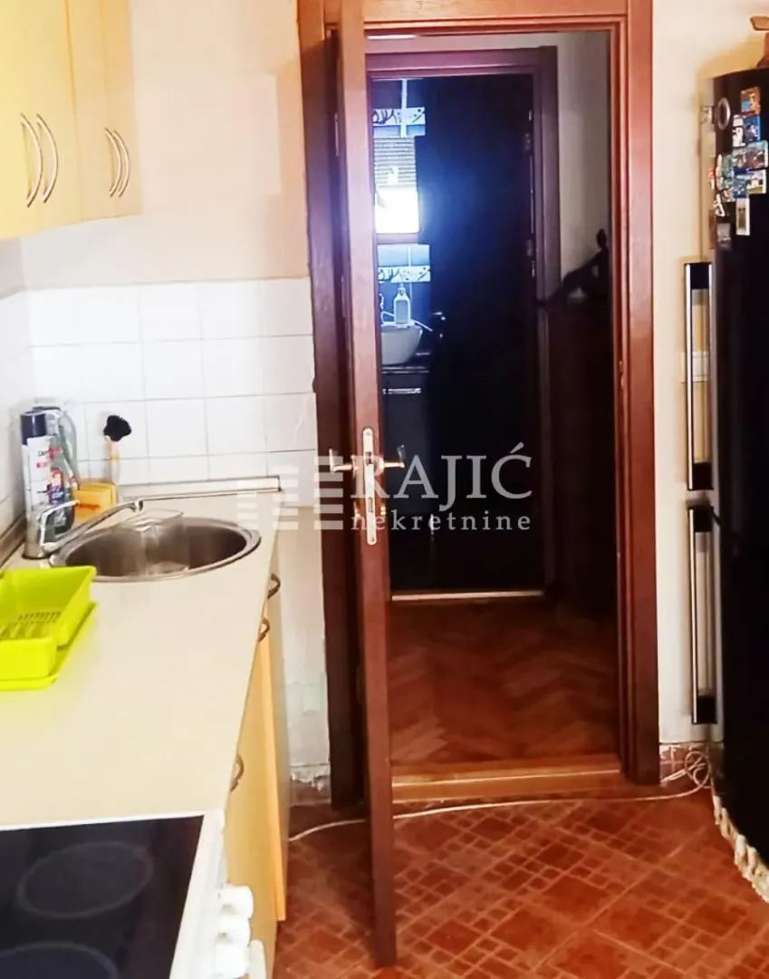 Small kitchen with a sink and a view towards the hallway.