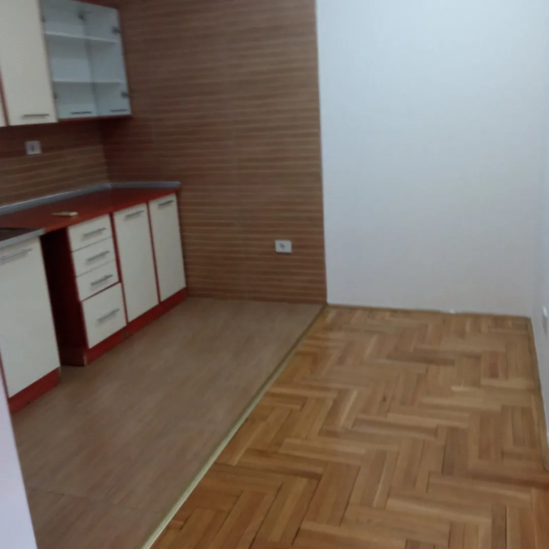 An empty kitchen space with installed cabinets and parquet flooring.