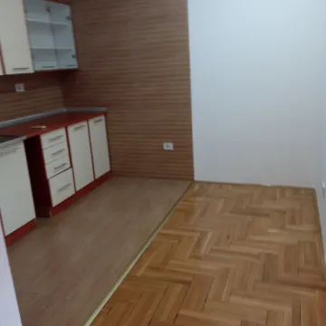 An empty kitchen space with installed cabinets and parquet flooring. - image 6