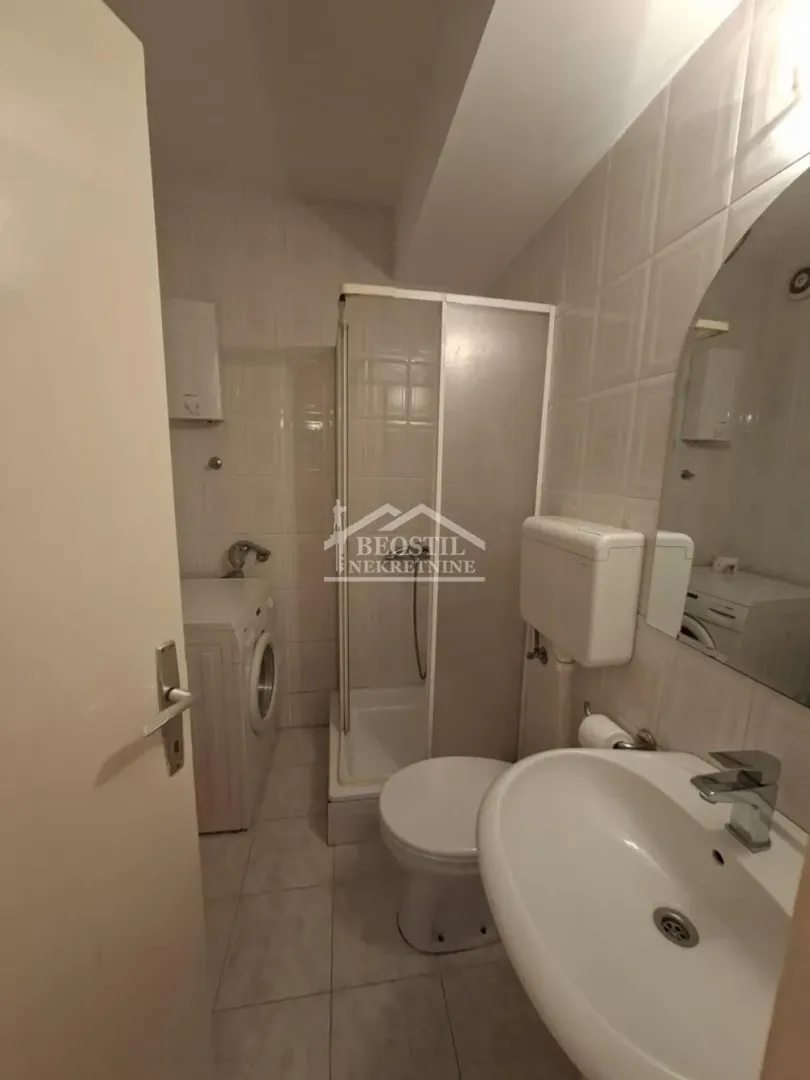 Bathroom equipped with a shower cabin, washbasin, toilet, and washing machine.