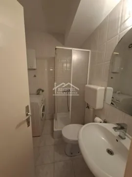 Bathroom equipped with a shower cabin, washbasin, toilet, and washing machine. - image 6