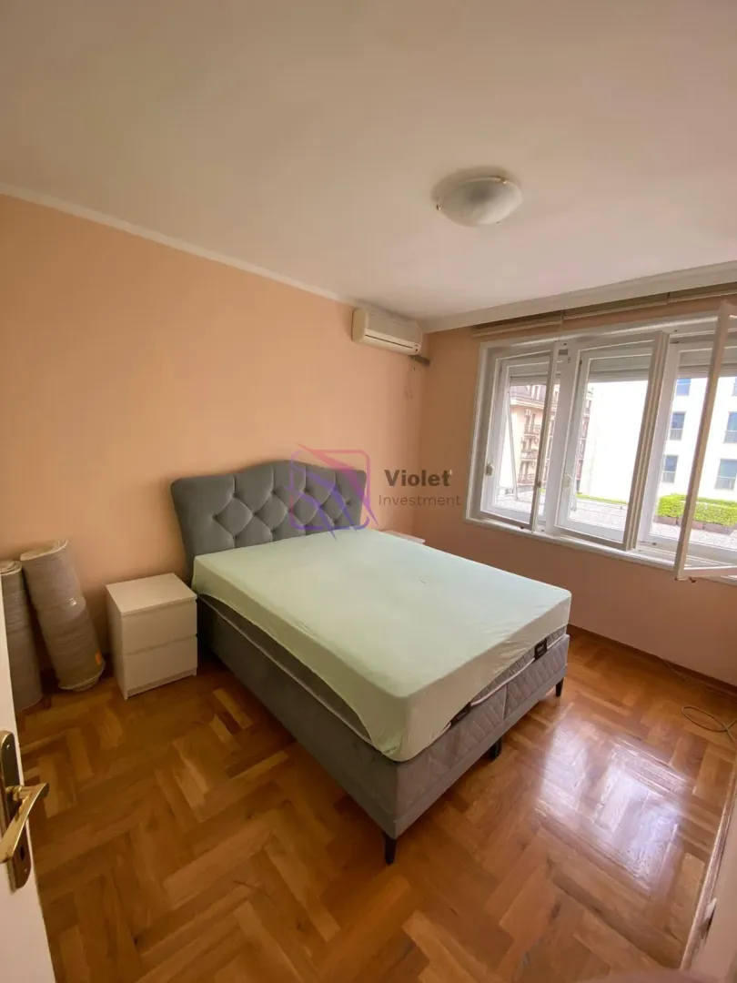 Namještena spavaća soba sa bračnim krevetom, noćnim stočićima i prozorom.