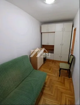 Manja spavaća soba sa zelenim kaučem, plakarom i drvenim podom. - image 6