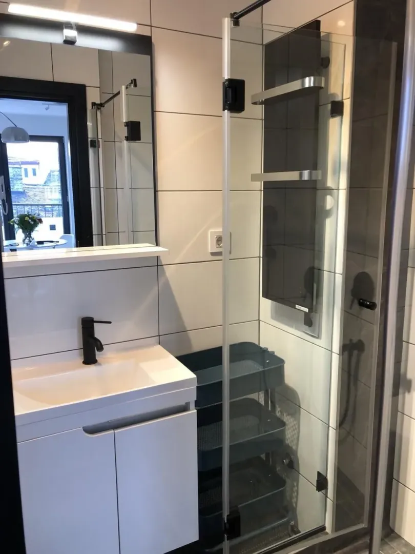 Modern bathroom with a washbasin, mirror and shower cabin.