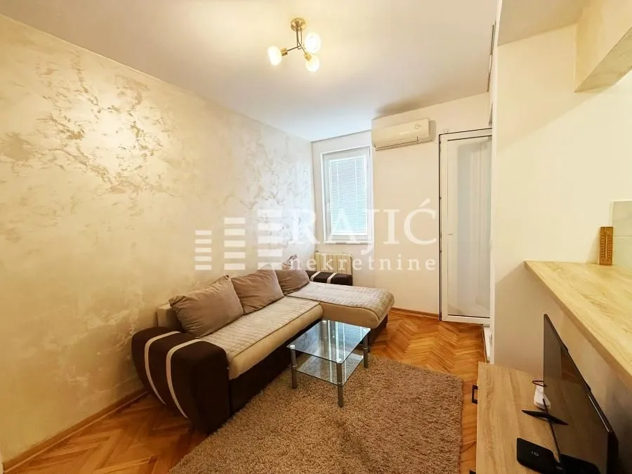 Living room with a sectional sofa and parquet flooring.