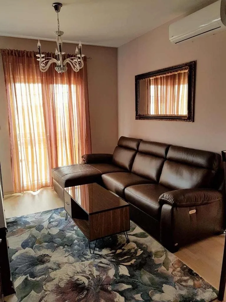 Living room with a leather sofa, coffee table, and balcony doors.