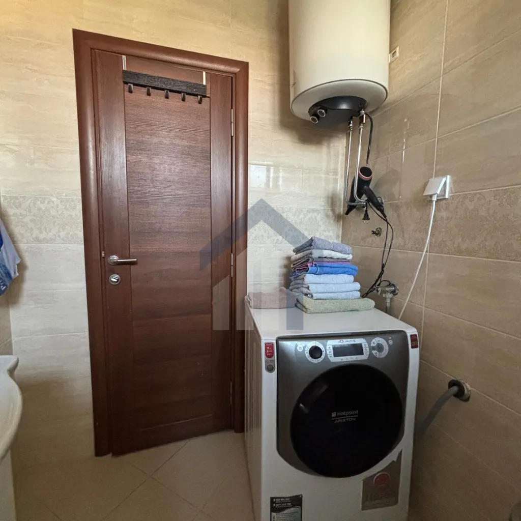 Bathroom with a washing machine, water heater, and wooden door.