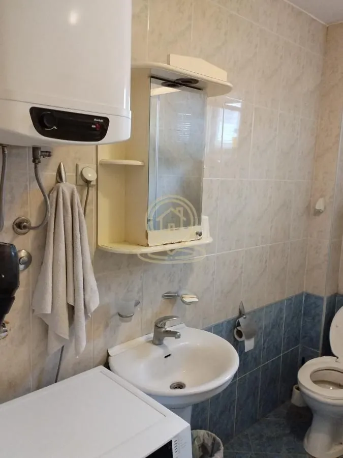 Kupatilo opremljeno umivaonikom, WC šoljom, bojlerom i ogledalom sa ormarićem.