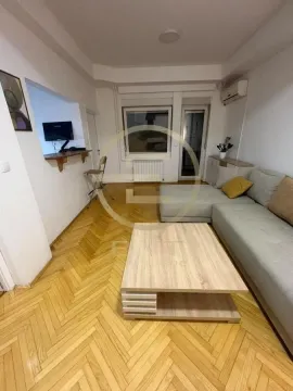 Dnevna soba sa ugaonom garniturom, drvenim stočićem i parketom na podu. - image 2