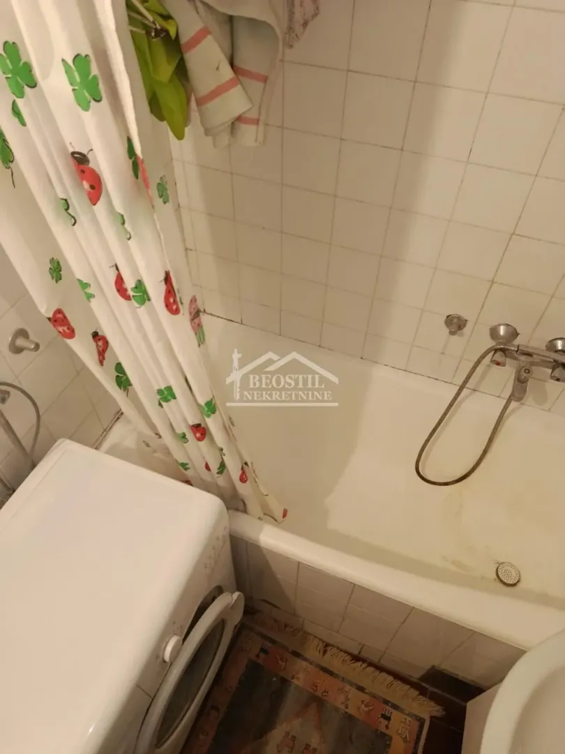 Smaller bathroom with a bathtub, shower curtain, and washing machine.