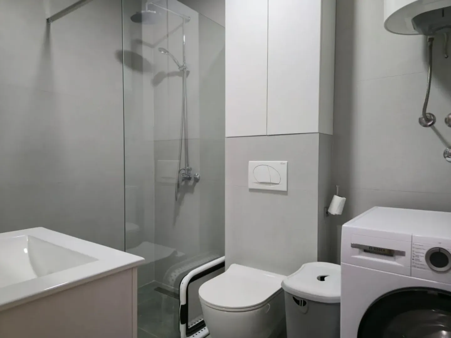 Moderne opremljeno kupatilo sa tuš kabinom i veš mašinom.