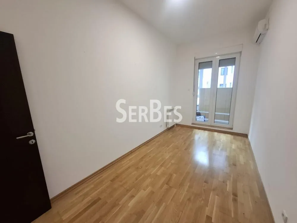 Empty bright room with parquet flooring and balcony doors.
