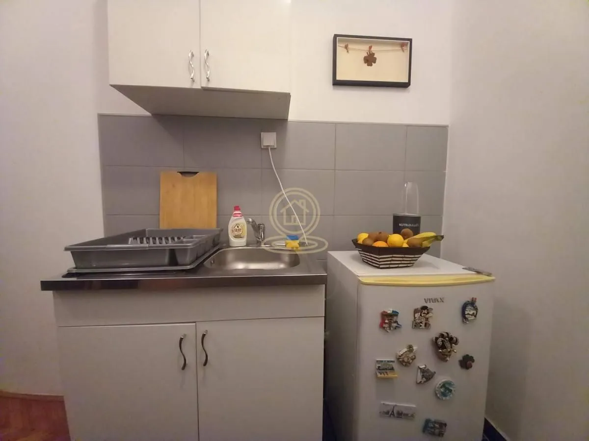 Small kitchen with a sink, cabinetry, and a refrigerator.