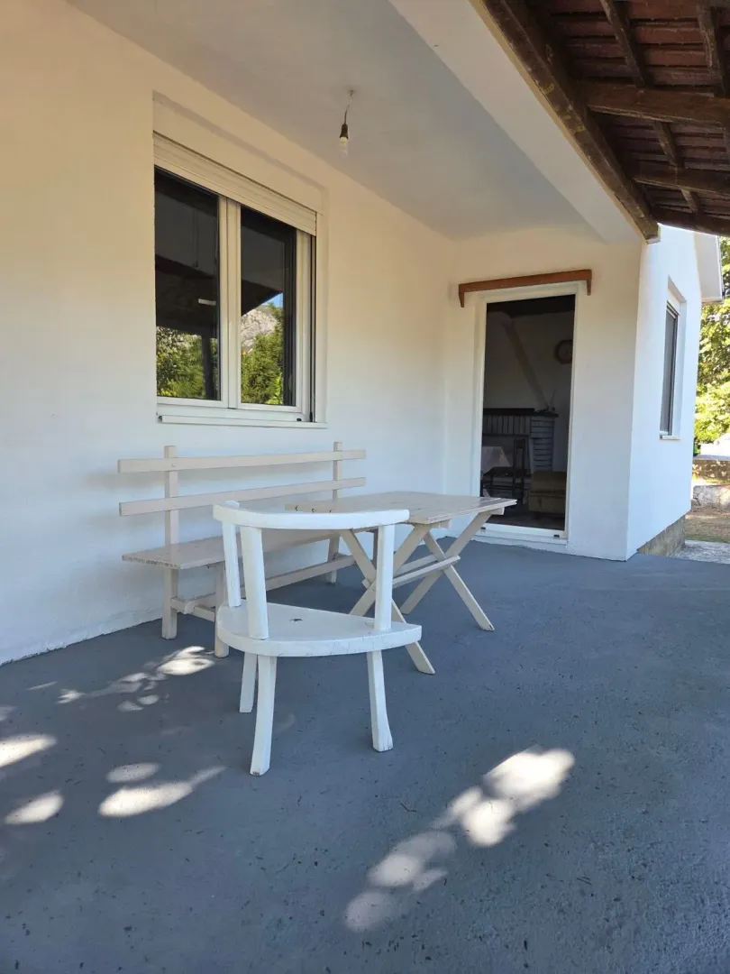 Natkrivena terasa ispred kuće sa garniturom za sjedenje.